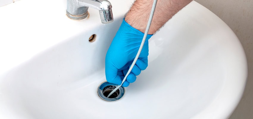 Plumber snaking a bathroom sink drain