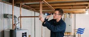 plumber inspecting copper pipe in basement/water heater