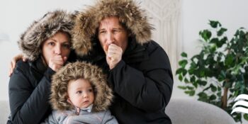 family in coats cold and huddled together heater out