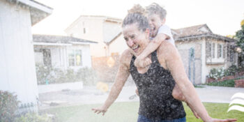mom and son running through sprinkler